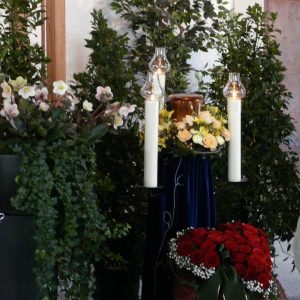aufgebahrte Urne mit Blumenschmuck und Kerzen